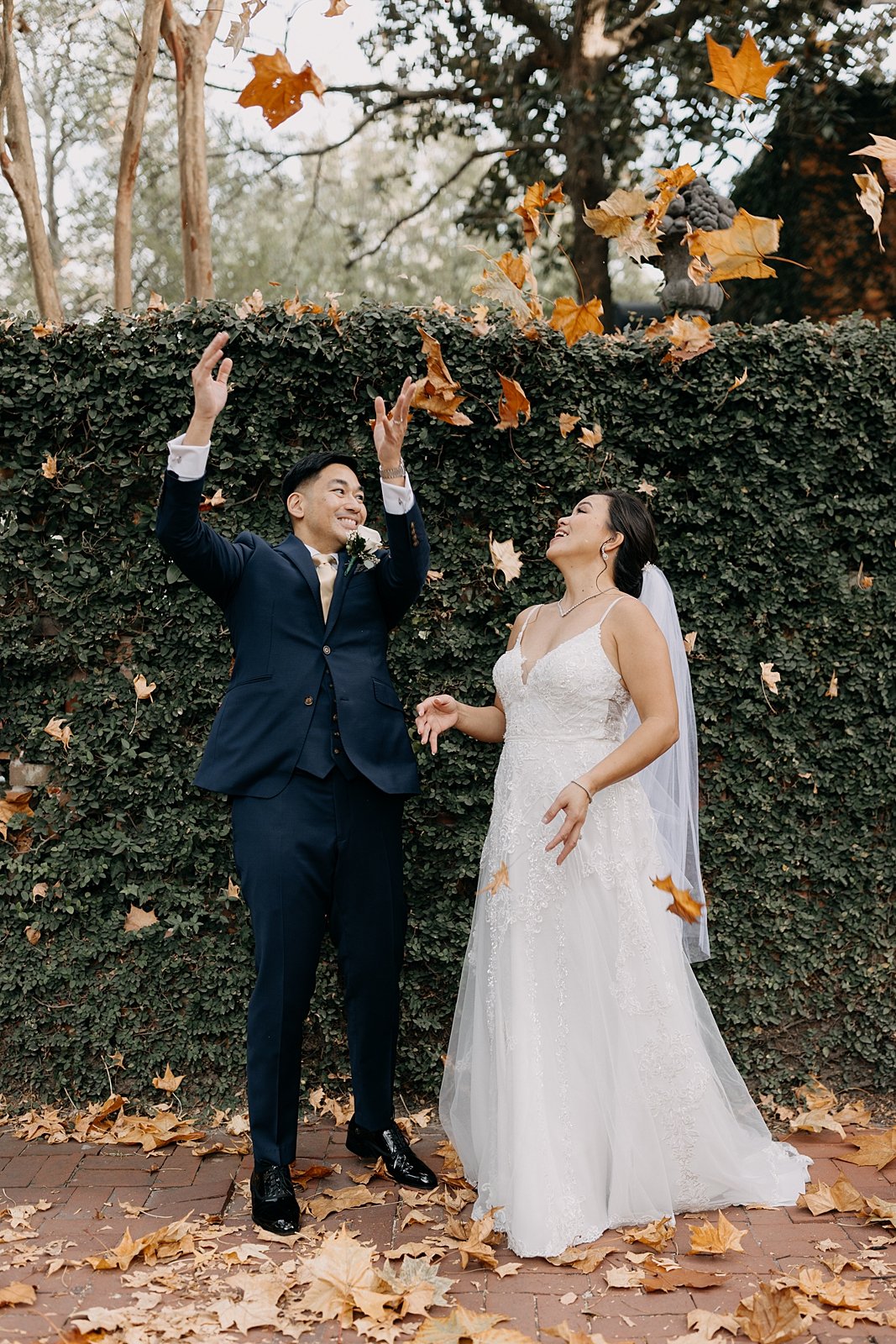 bride and groom throw leaves for fall wedding in savannah